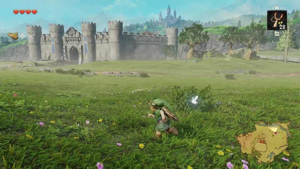 Link running through a flower-filled meadow toward the long crenellated outer wall of Castle Town, its gatehouse flying blue banners, with Hyrule Castle on the hill behind