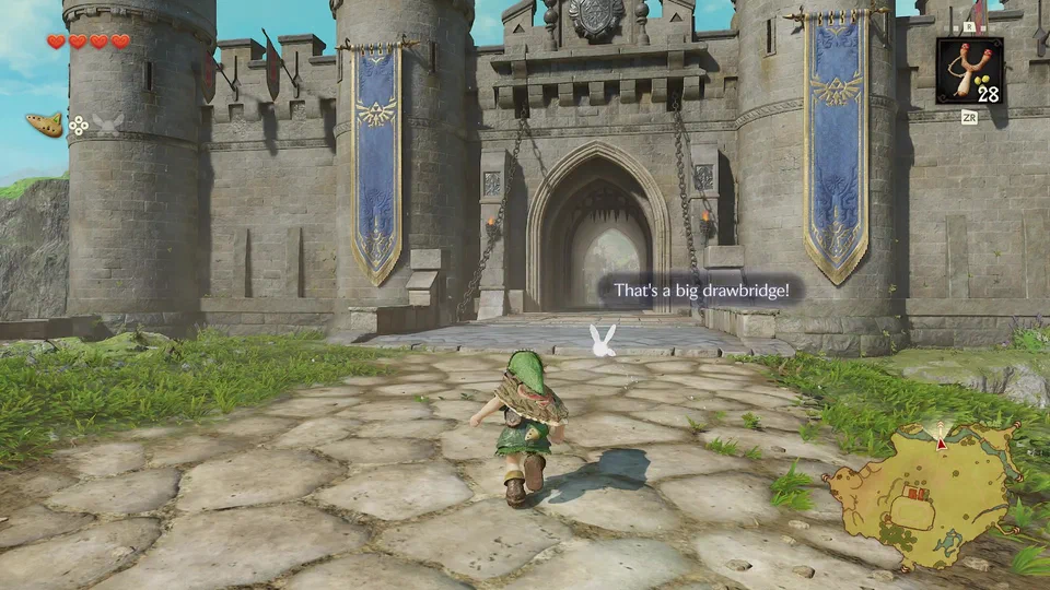 Link and Navi on the stone approach to the Castle Town gatehouse, drawbridge down, portcullis raised, Hylian Crest banners on both towers, with Navi's floating comment: That's a big drawbridge!
