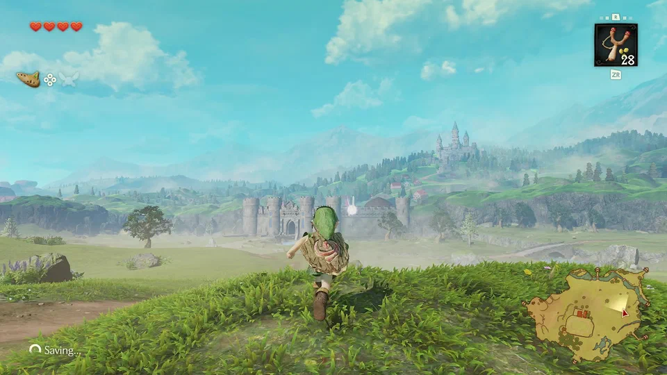 Link running through tall grass toward the Castle Town gate and drawbridge, Hyrule Castle on the hill behind, a stone bridge to the right, with a Saving... indicator in the corner
