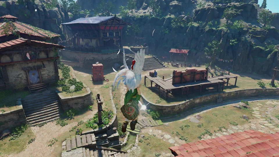 Overhead view of young Link gliding down over Kakariko Village holding a flapping white Cucco, with red-roofed houses, a large blue-roofed two-storey house, the brick-and-timber Cucco pen, stone stairs and bunting strung between buildings below, cliffs behind