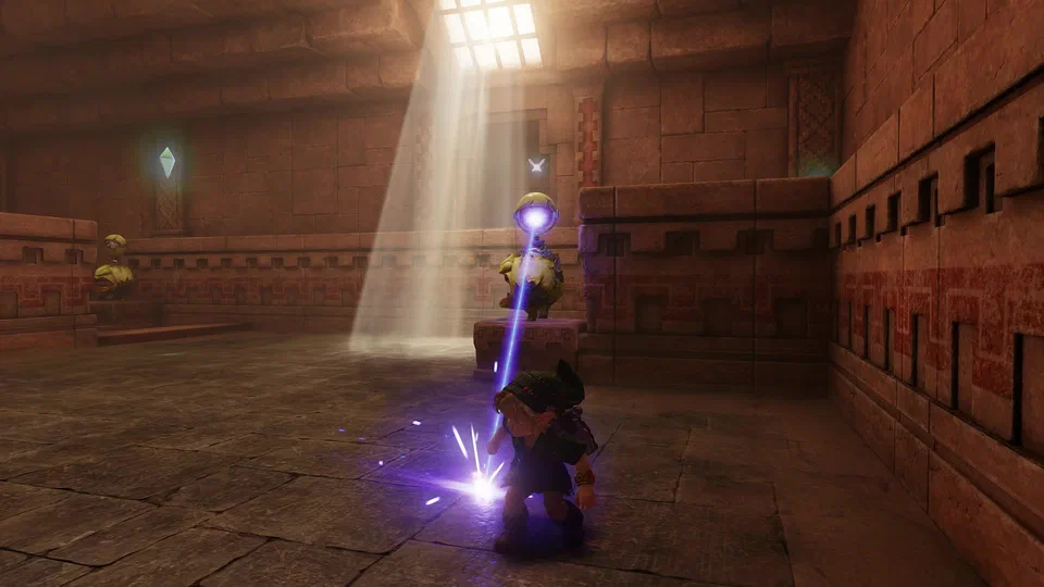 Young Link crouching on the stone floor of a sandstone Spirit Temple room as a Beamos statue on a pedestal fires a purple laser beam down at him; a second Beamos stands to the left and a shaft of light falls from a barred skylight